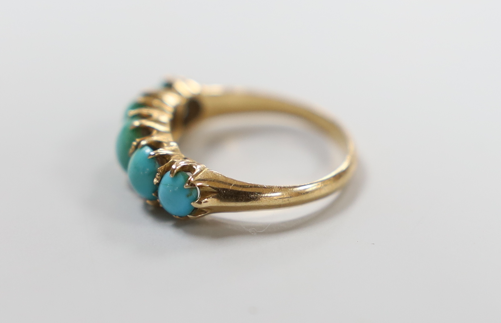 A yellow metal and graduated five stone cabochon turquoise set half hoop ring, size G/H, gross weight 2.4 grams.